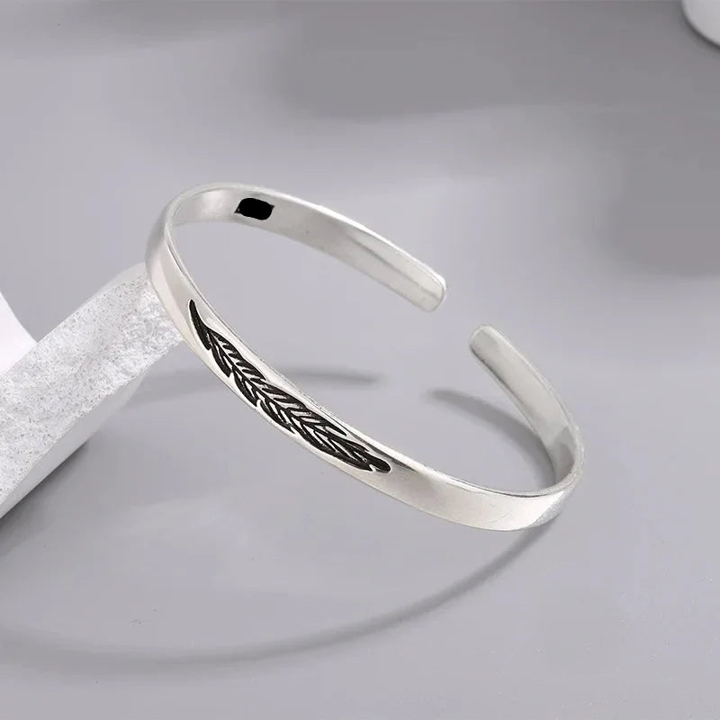 Åben armring med sølvfarvet fjer