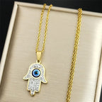 Långt halsband med skyddshänge med onda ögat och arabisk Hand of Fatima i guldfärg