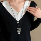 Långt halsband med silverfärgat spiralformat hängsmycke