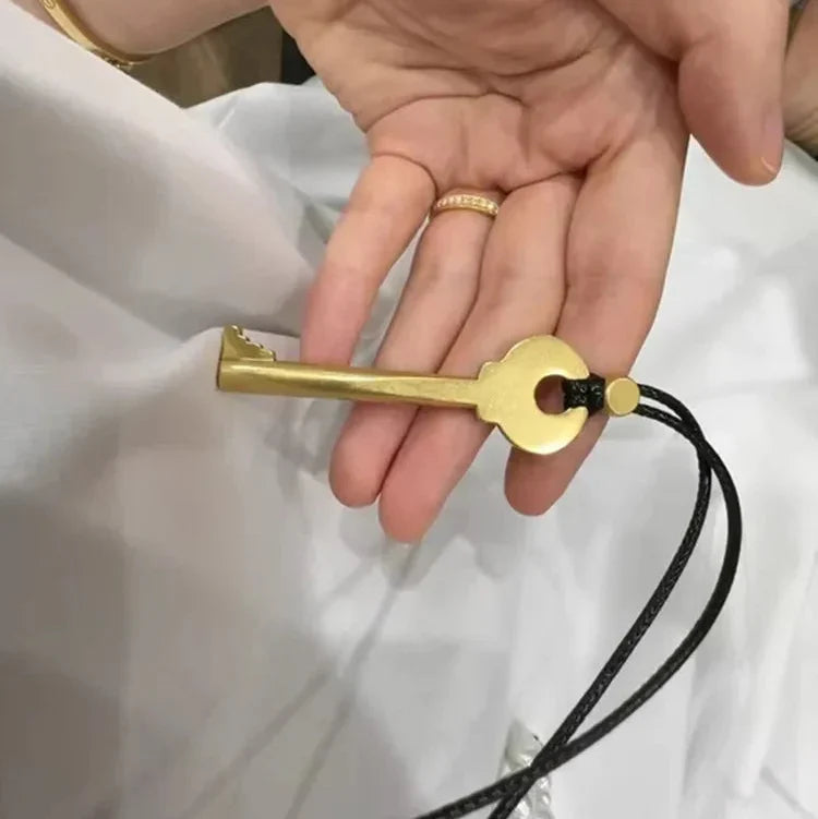 Lang halskæde med snor og nøglevedhæng i guldfarve