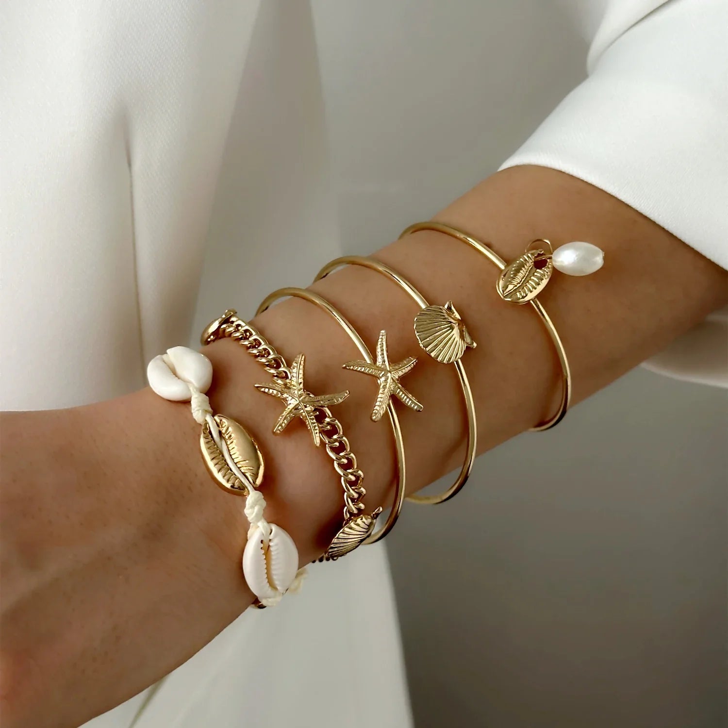 Sett med 5 gullfargede armbånd med skjell og stjerne